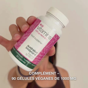 Gros plan d’une main tenant le flacon de complément alimentaire Vitamine B12, ouvrant le couvercle et versant des gélules blanches et lisses – présentation du produit pour un usage quotidien afin de soutenir l’énergie, l’immunité, le système nerveux et réduire la fatigue.