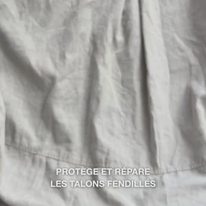 Gros plan sur une main prélevant une texture riche et crémeuse du Heel Repair et la massant doucement sur la peau sèche et fissurée du talon : la consistance épaisse est visiblement absorbée, adoucit et hydrate les zones rugueuses, tandis que l’urée à 25 %, le beurre de karité et l’huile d’arbre à thé apaisent et protègent la peau.