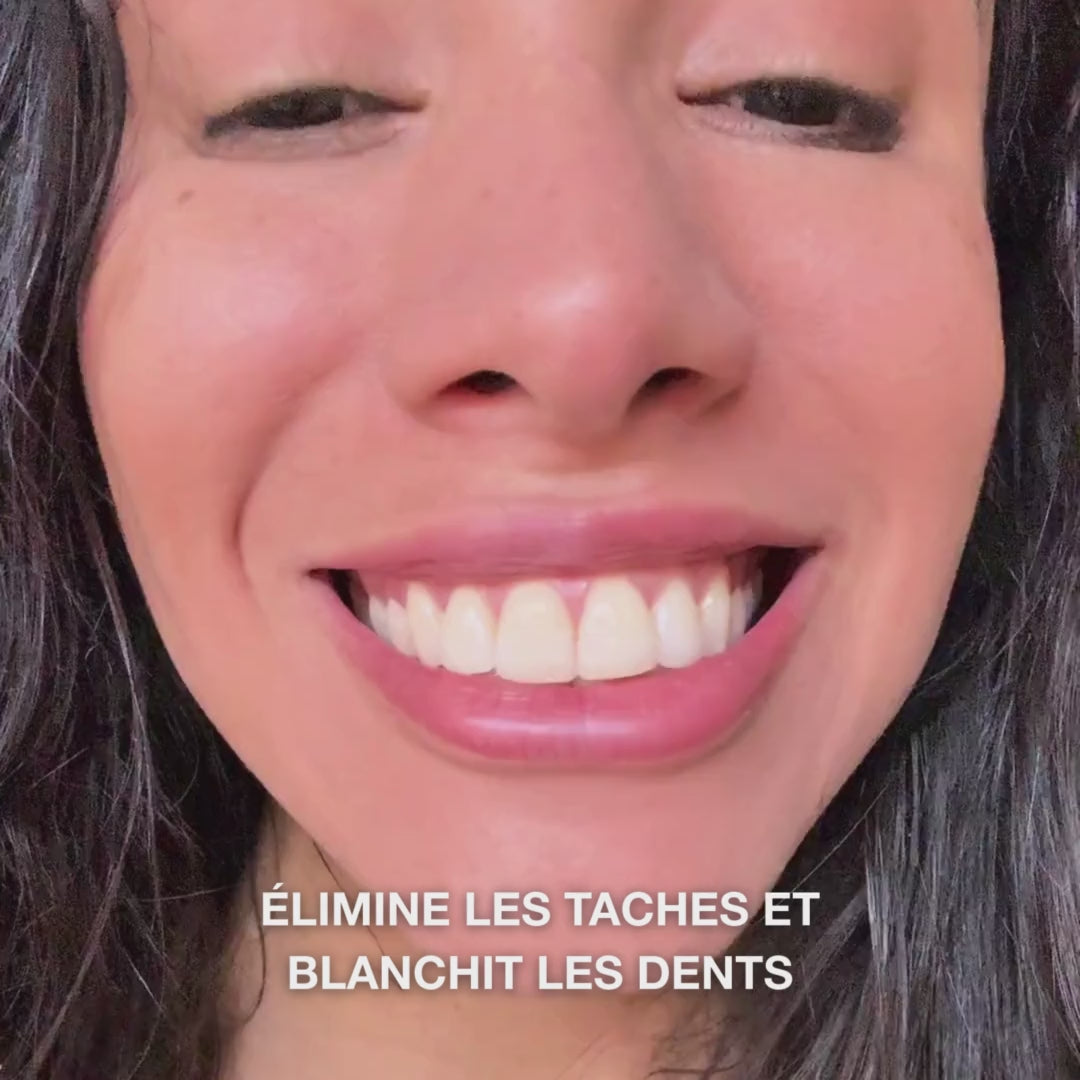 Gros plan d’une main déposant une noisette de dentifrice blanchissant sur une brosse à dents et brossant en mouvements circulaires : la pâte fine avec silice hydratée, alumine et menthol élimine les taches, renforce l’émail et laisse une haleine fraîche 